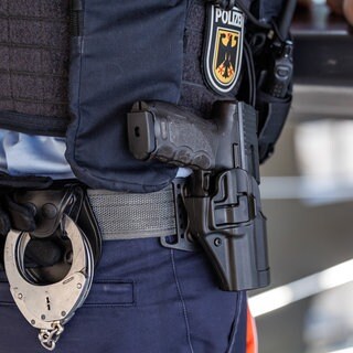 Ein Polizist mit Handschellen und Waffe