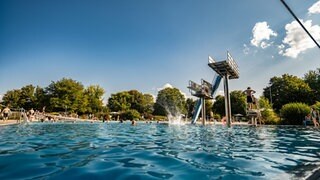 Im Tübinger Freibad schwimmen Menschen und springen vom Sprungturm. Durch den Hitzesommer gab es viele Besucher