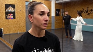 Tanzlehrerin Lea Grünwald steht in ihrer Tanzschule in Lahr. Im Spiegel hinter ihr ist ein tanzendes Brautpaar zu sehen.