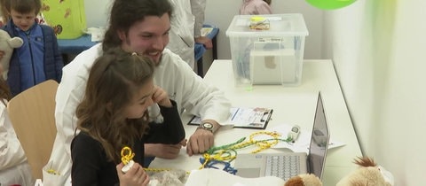 Ein Medizinstudent erklärt einem kleinen Mädchen etwas