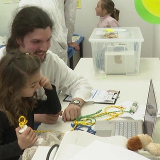Ein Medizinstudent erklärt einem kleinen Mädchen etwas