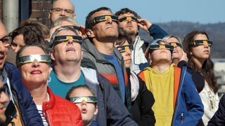 Symbolbild: Besucher mit Schutzbrillen blick in den Himmel