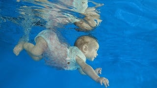 Säugling taucht in Schwimmbecken