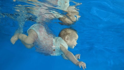 Säugling taucht in Schwimmbecken