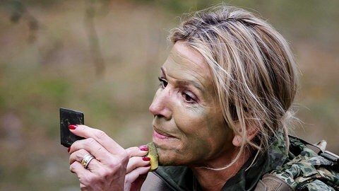Königin Máxima malt sich grüne Tarnfarbe ins Gesicht. 
