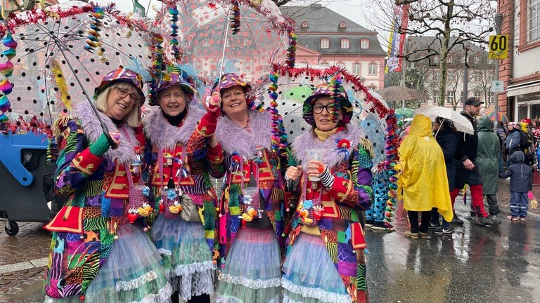 Auch diesen Frauen hier kann der Regen nichts anhaben. Im Gegenteil: So schön bunt kostümiert fällt der graue Himmel schon fast nicht mehr auf.