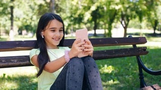 Mädchen mit Smartphone auf Parkpank