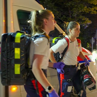 Die Rettungssanitäterinnen Alina Peschers und Stephanie Dahlem vor einem Krankenwagen. Sie arbeiten in der Nachtschicht.