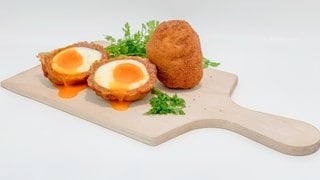 Schottische Eier auf einem Holzbrett angerichtet. Super zum Teilen und ein perfekter Party-Snack.