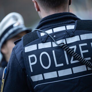 Symbolbild: Ein Polizist steht bei einem Einsatz an der Straße.