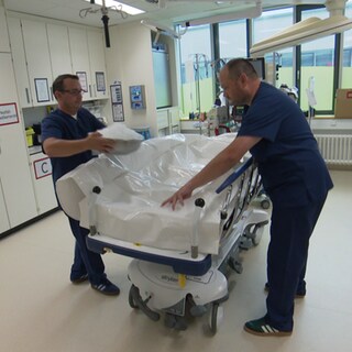 Ein Arzt der Notaufnahme befüllt einen Body Bag mit Eis um später einen Patienten zu kühlen.