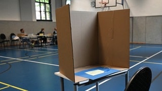Leere Wahlkabine aus Pappe in einer Turnhalle