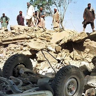 Afghanen blicken am 9.10.2001 auf die Trümmer des Gebäudes der von den Vereinten Nationen (UN) finanzierten Minenräumorganisation Afghan Technical Consultants in Kabul.