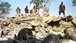 Afghanen blicken am 9.10.2001 auf die Trümmer des Gebäudes der von den Vereinten Nationen (UN) finanzierten Minenräumorganisation Afghan Technical Consultants in Kabul.