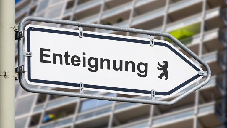 Richtungspfeil mit der Aufschrift ENTEIGNUNG vor einem Wohnblock