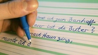Ein Analphabet schreibt in Köln Sätze zur Übung in ein Schulheft