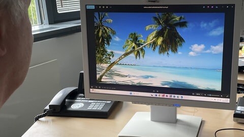 Ein Mann sitzt am Computer und sieht sich Urlaubsseiten an.