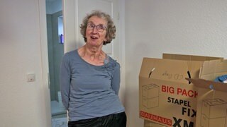 Ute Jantzer ist an Parkinson erkrankt und steht neben Umzugskartons in ihrem neuen Zuhause der Starck-Stiftung in Schweighofen