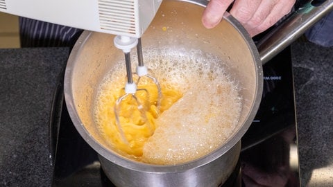 Stollenparfait, das Dessert zum Weihnachtsmenü: Ei wird in einer Schüssel aufgeschlagen.