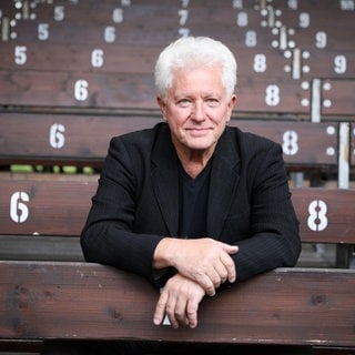 Schauspieler Miroslav Nemec sitzt auf einer Tribüne. In SWR1 Leute spricht er über seine Rolle des Kriminalhauptkommissar Ivo Batic im Tatort München.