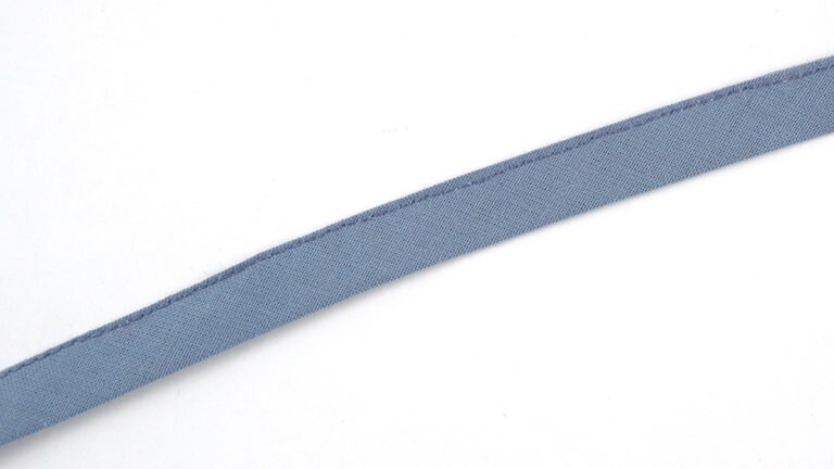 Ein 15 cm langes Stück Schrägband zurechtschneiden. Das Band der Länge nach falten und knappkantig zusammensteppen.