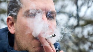 Mann pafft eine Zigarette mit viel Rauch: Rauchen ist ein starker Altersbeschleuniger für die Haut.