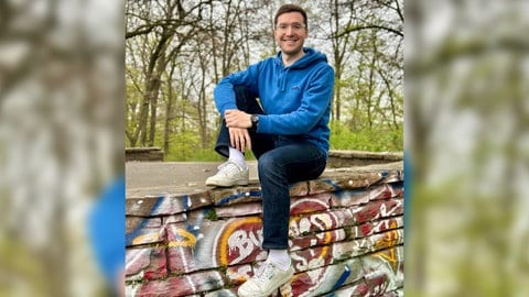 Bestsellerautor David Nelles sitzt auf einer mit Graffiti besprühten Mauer. | Wie wär's mit konkreten Lösungen? David Nelles macht Vorschläge beim Klima und anderen Streitthemen