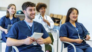 Vier Medizinstudierende sitzen gut gelaunt bei einer Konferenz. Die Anzahl an Medizinstudierenden pro 100.000 Einwohnern ist in Rheinland-Pfalz bundesweit im unteren Viertel.
