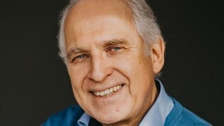 Zeichner und Autor Werner Tiki Küstenmacher lacht in die Kamera. 