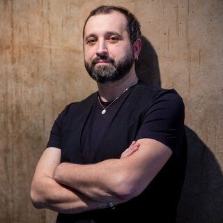 Soziologe und Polarisierungsforscher Holger Marcks steht mit verschränkten Armen vor einer Holzwand.
