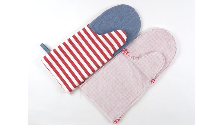Den Handschuh aus Futterstoff links auf links in den Handschuh aus Oberstoff schieben und an der Eingriffkante aufeinanderheften. Knappkantig mit langem Geradstich zusammennähen.