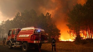 Feuerwehrleute versuchen in der Nähe von Le Porge im Südwesten Frankreichs mit einem Waldbrandlöschfahrzeug, die brennenden Bäume zu löschen.