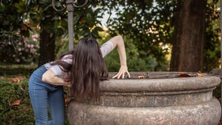 Brünette Frau stellt gruseliges Horror-Motiv dar mit verdrehten Armen
