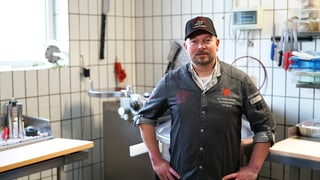 Metzgermeister und Maultaschenkänig Olli Häcker stecht in seiner Metzgerei. Er hat die Hände auf den Hüften und schaut in die Kamera.