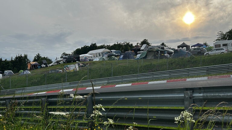 Campingplatz bei Rock am Ring 2025 im Sonnenuntergang, im Vordergrund die Rennstrecke.