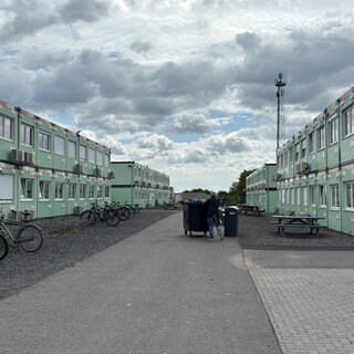 Rechts und links auf dem Bild sieht man aufeinandergestapelte Container, in denen die Schülerinnen und Schüler des Are-Gymnasiums unterrichtet werden.