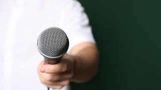 Ein Mann hält ein Mikrofon und führt ein Interview. Symbolfoto.