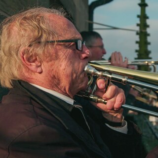 Rolf Klostermann ist 89 Jahre alt. Er steht mit anderen Posaunenspielern auf einem Kirchturm. 