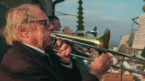 Rolf Klostermann ist 89 Jahre alt. Er steht mit anderen Posaunenspielern auf einem Kirchturm. 
