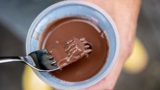 Ein junger Mann isst einen Schokoladenpudding mit einer Gabel. Archivfoto.