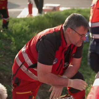 Notarzt Björn Hossfeld kniet mit anderen Rettungskräften an einer Unfallstelle.