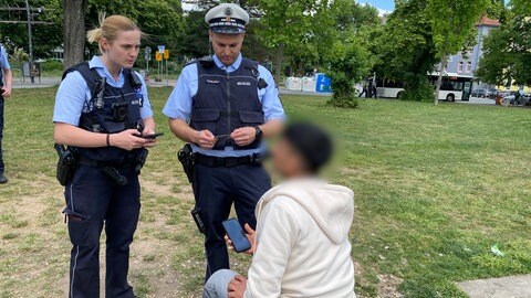 Eine Polizistin und ein Polizist kontrollieren in Heidelberg einen jungen Mann in der Nähe des Hauptbahnhofs 