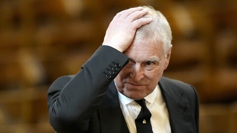 Der ehemalige Prinz Andrew fasst sich mit seiner Hand an den Kopf.