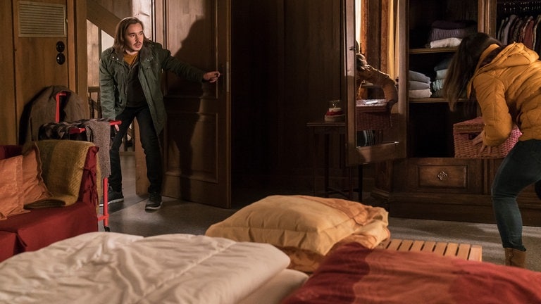 Sebastian steht Schmiere, während Jenny eine Kiste im Schrank ihrer Eltern versteckt