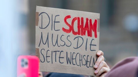 Ein Demonstrationsschild mit der Aufschrift "Die Scham muss die Seite wechseln".