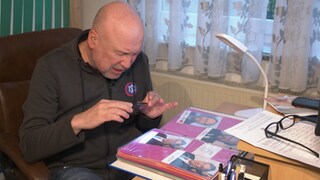 Achim Pfeifer sitzt an seinem Schreibtisch und betrachtet einen Teil seiner Autogramm- und Handschriftensammlung.