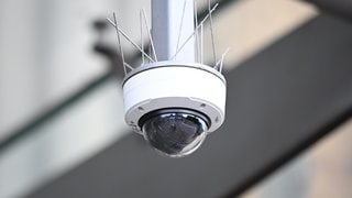 Eine Überwachungskamera hängt vor einem Bahnhof