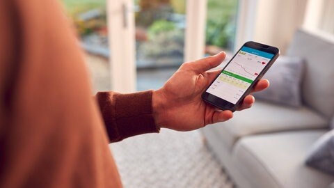 Nutzer einer Fitness-App schaut auf sein Handy