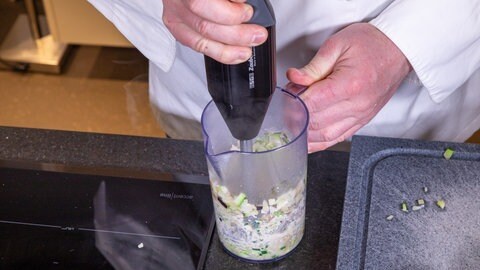 Gemüse als Aufstrich zubereiten: Mit einem Handmixer werden in einem hohen Gefäß Zucchini, Auberginen und Zwiebeln zerkleinert.