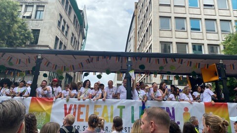 Menschen fahren auf einem Wagen bei der Parade des CSD Stuttgart 2025 mit.